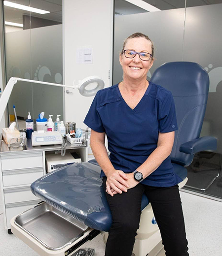 Nicole, the owner of Feet In Motion, sitting on the clinic chair with a smile.